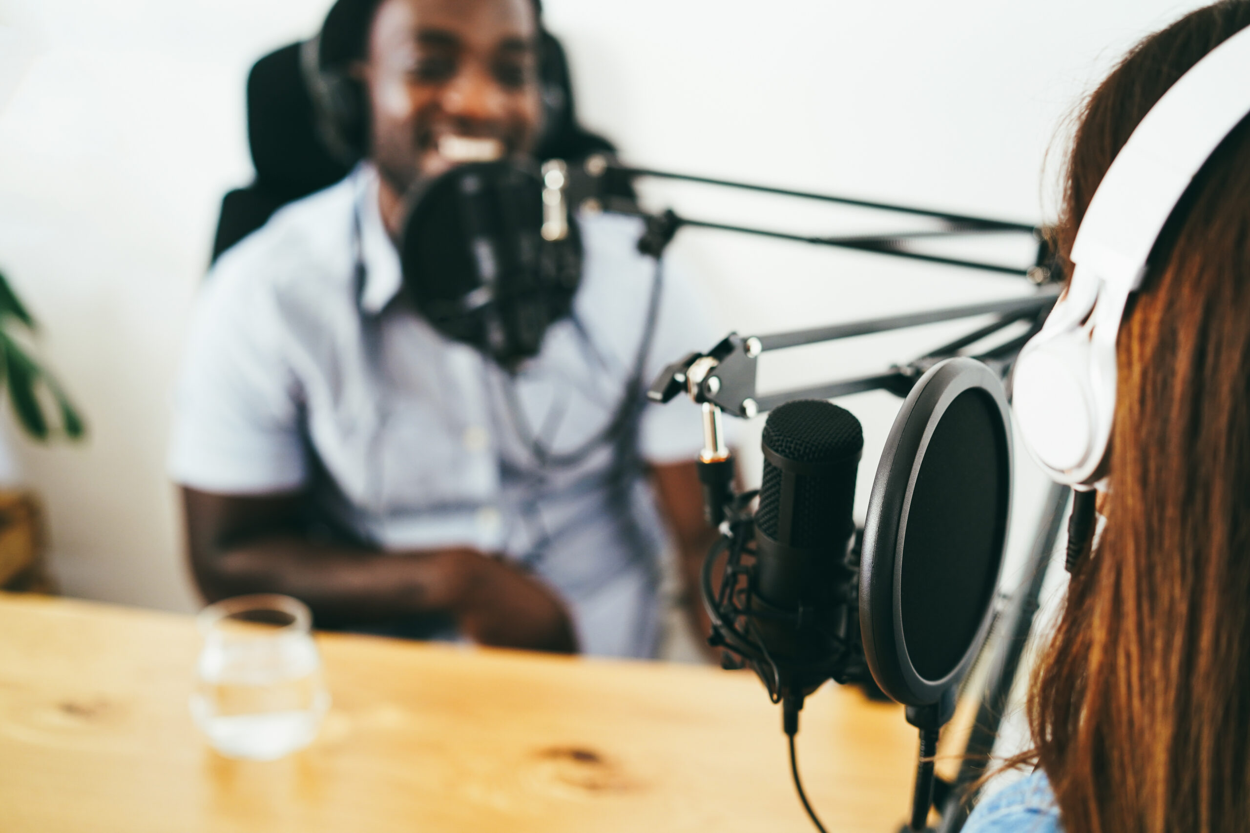 Multiracial hosts streaming podcast together at home studio - Focus on microphone pop filter