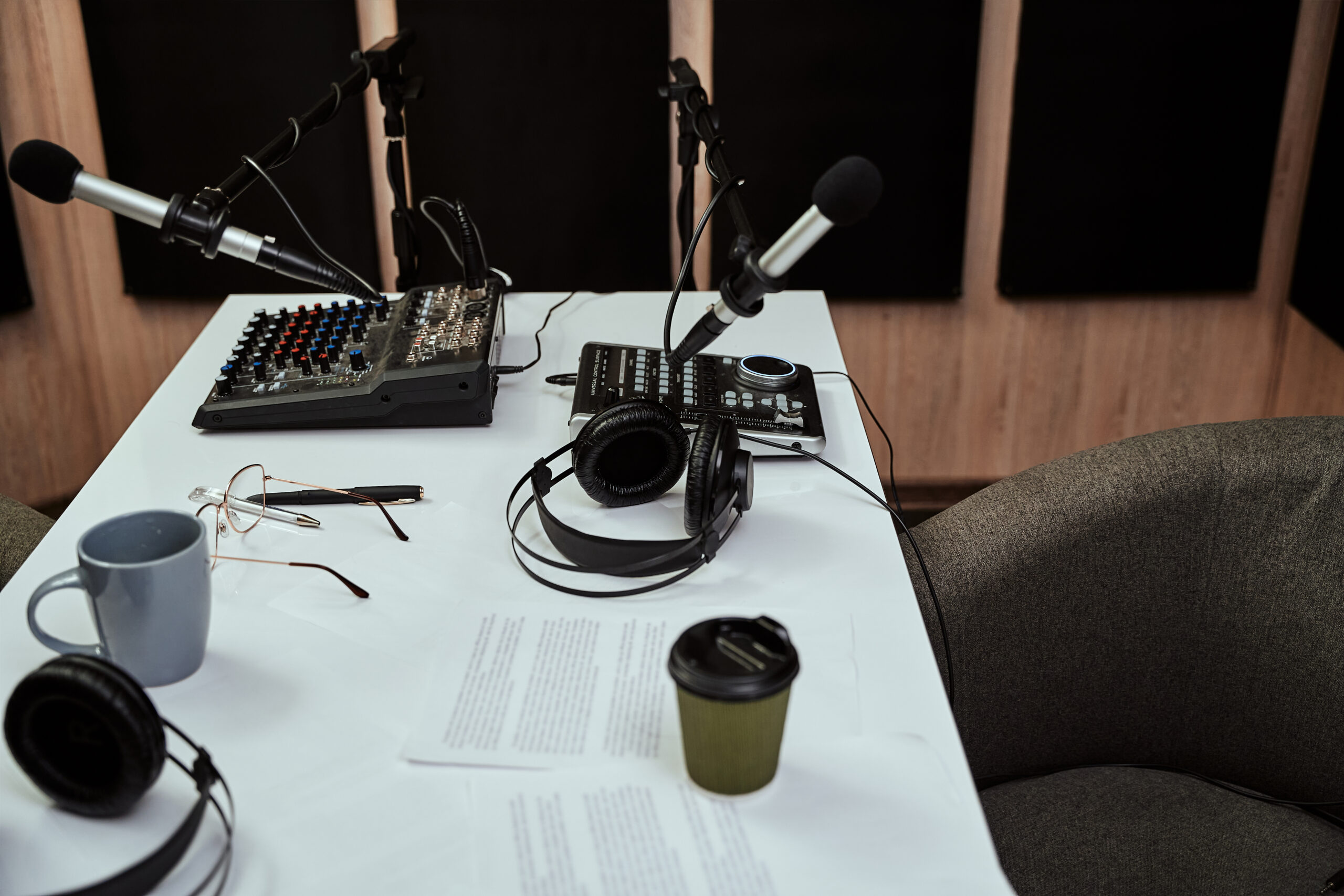 Working place of radio host. Close up of microphones, headphones, sound mixing desk, script on the table in recording studio or broadcast room. High angle. Selective focus. Horizontal shot